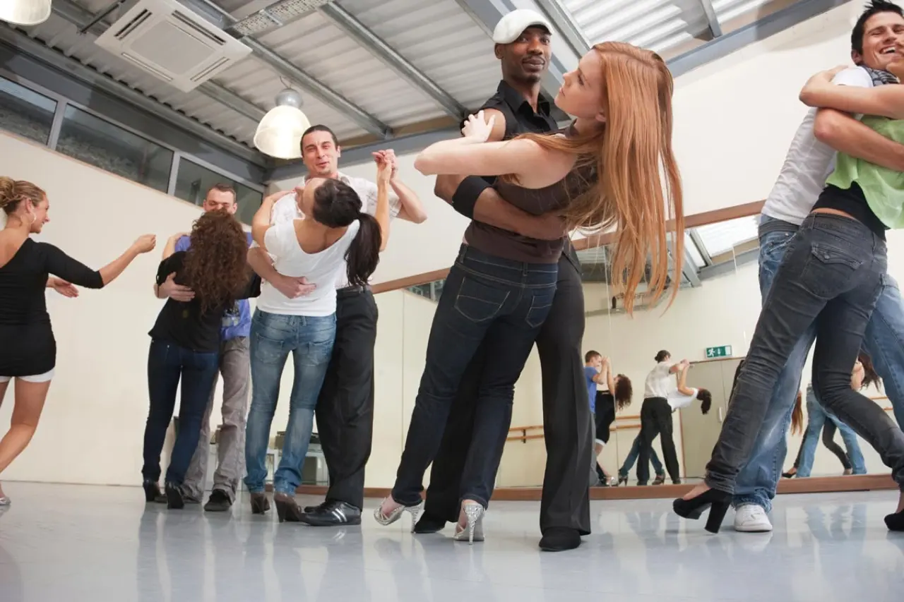 Personnes pratiquant des pas de danse dans une salle lumineuse